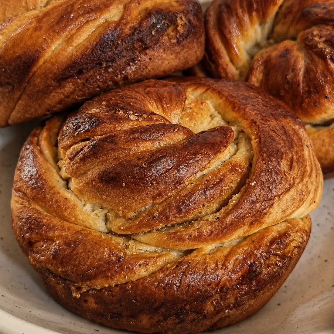 A glazed cardamom knot, close, in a stoneware dish.